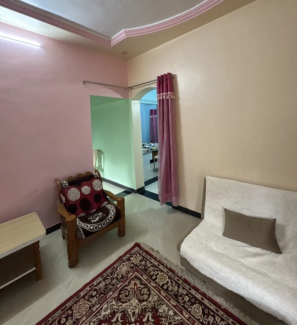 Corner of the hall with a wooden sofa chair and an arched doorway through to the green kitchen