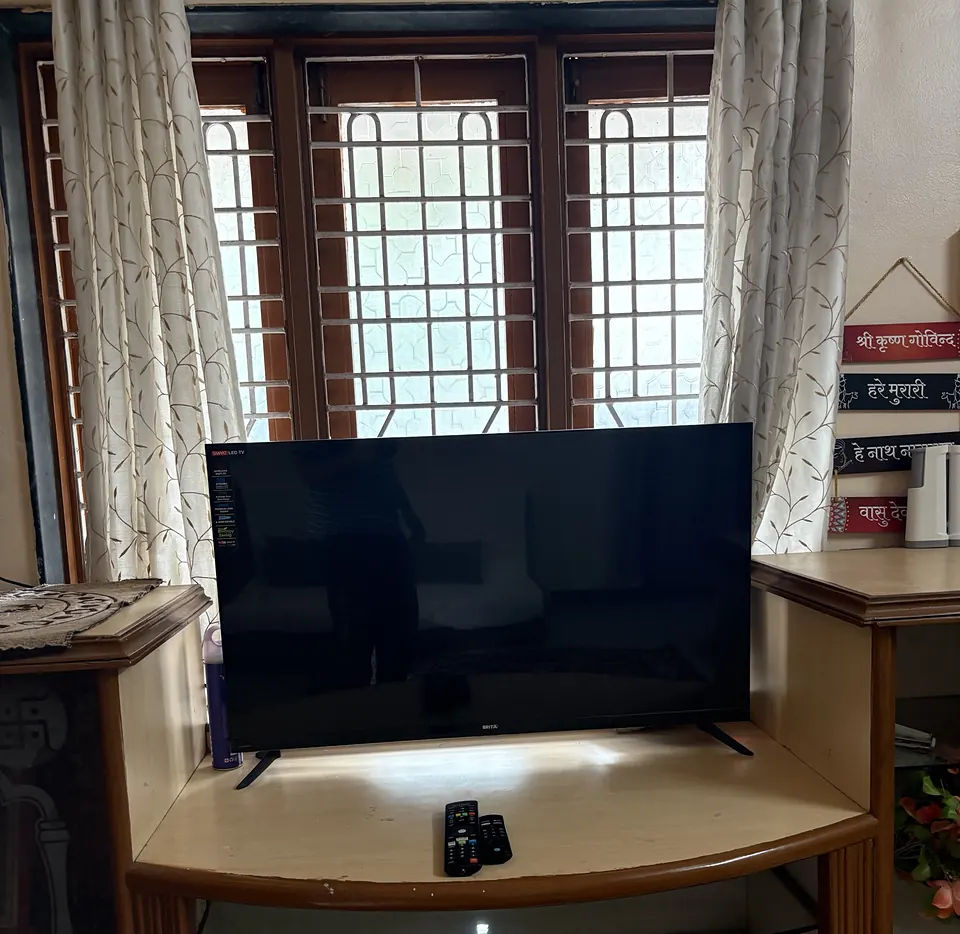 Smart LED TV on a wooden TV unit in front of a window