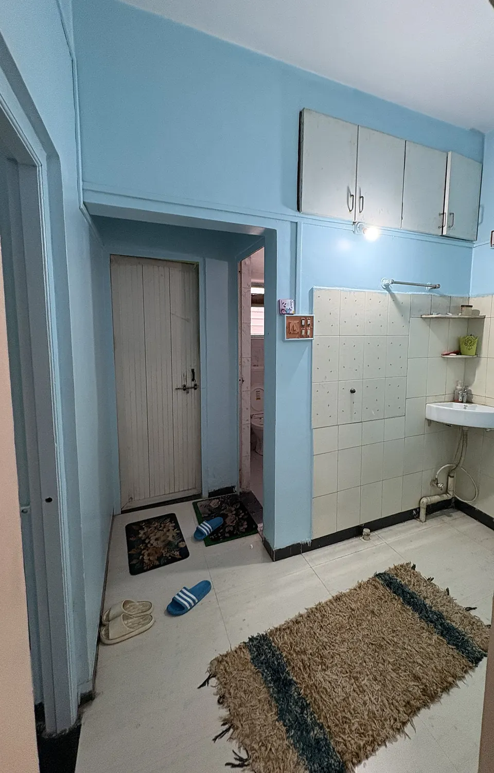 Washbasin area with tiled wall, cabinets and doors to the toilets