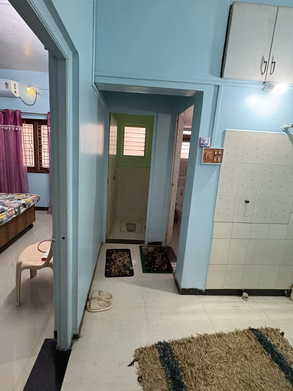 Passage with the washbasin wall, a door to the Indian-style toilet and a doorway to the bathroom
